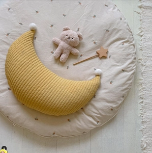 Close-up of quilted moon pillow, floral round mat and plush bear for nursery decor