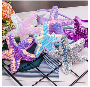 Detail shot of five colorful sequin starfish headbands displayed on a black wire rack
