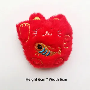 Detail showing red plush lucky cat brooch with gold embroidery, size 6cm by 6cm
