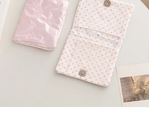 Close-up view of pink bow passport holder featuring a polka dot interior and storage slots