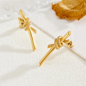 Elegant gold-tone knot stud earrings featuring shimmering cubic zirconia on white background