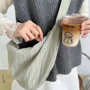 Detailed close-up of light green pleated crossbody bag with a star charm accessory