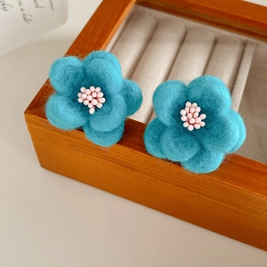 Macro de boucles d'oreilles fleurs en feutre bleu avec étamines de perles fines