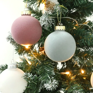 Pink, grey, and white matte Christmas balls hanging on a warm lit festive tree