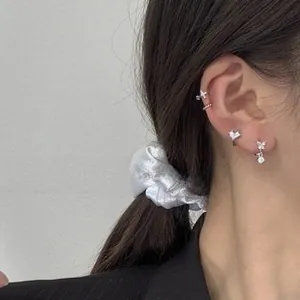 Close-up of butterfly and geometric silver earrings with crystals on female model