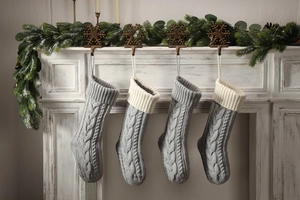 Set of 4 knitted cable stitch Christmas stockings hanging on a white festive fireplace