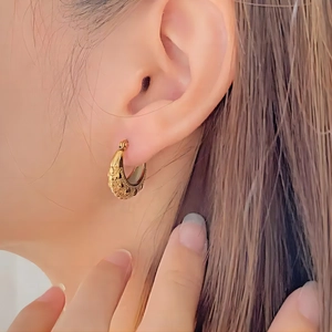 Detailed view of vintage gold-plated C-shaped earrings with intricate heart texture patterns