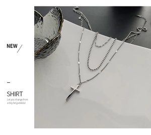 Detailed view of triple-layered silver stainless steel necklace with a cross pendant