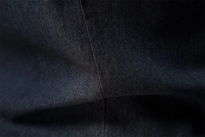 Macro shot of dark denim fabric with high-density twill weave and precise center stitching