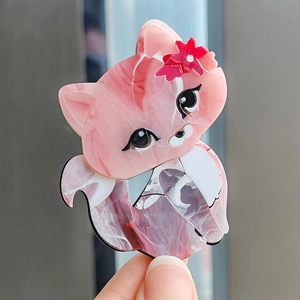 Close-up of cute pink and white marble-textured acrylic cat brooch with red flower