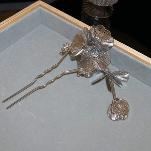 Detail of silver wavy hairpin featuring three hollow floral motifs on velvet display