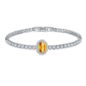 Macro detail of silver tennis bracelet with oval yellow gemstone and secure watch clasp