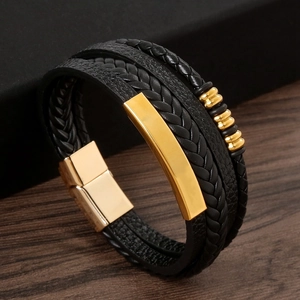 Close-up of layered black leather bracelet with gold magnetic clasp on wood background