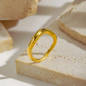 Macro shot of gold irregular wavy ring displayed on a natural beige porous stone