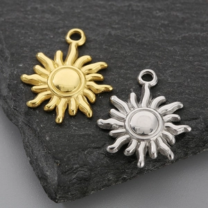 Macro detail of gold and silver sun pendants on grey stone for DIY jewelry making