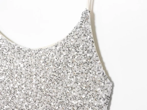 Détail des paillettes argentées scintillantes et des fines bretelles sur une robe blanche