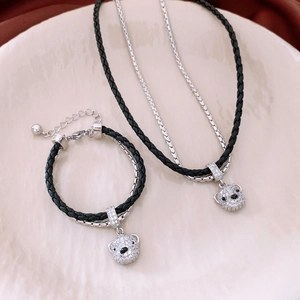 Close-up of bear pendant jewelry set with black woven cord and silver metal chain