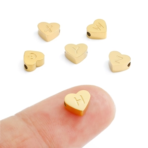 Close-up of polished gold heart-shaped alphabet beads for DIY jewelry making and beading