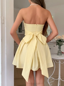 Vue arrière d'une mini robe jaune dos nu avec grand nœud papillon et jupe trapèze