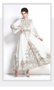 Dettaglio di un abito lungo bianco con stampa paisley e cintura in tessuto coordinato