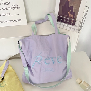Detail of purple and mint canvas tote bag with Rêve embroidery in a lifestyle setting