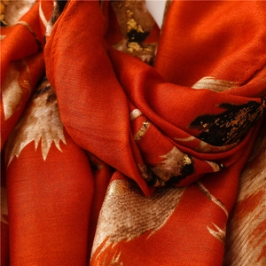 Detail of soft orange pashmina scarf with gold foil leaf patterns and delicate fabric texture