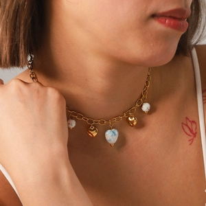 Gold chain necklace with ceramic heart pendants worn by a model on the collarbone
