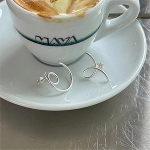 Minimalist 925 sterling silver spiral stud earrings shown on a modern coffee table