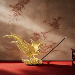 Golden phoenix incense holder in antique style with detailed relief on red desk