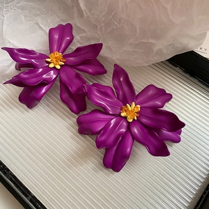 Detail of purple acrylic flower earrings with yellow crystal stamens for summer beach style