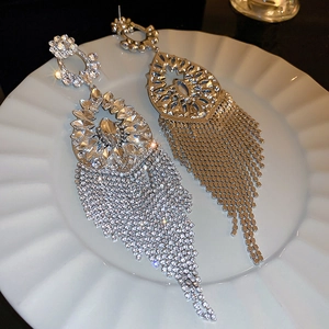 Macro shot of silver drop earrings with rhinestones and tassels on a ceramic plate