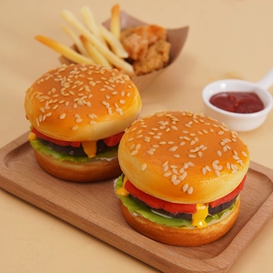 Modèle de burger artificiel en PU réaliste avec pain au sésame exposé sur un plateau en bois