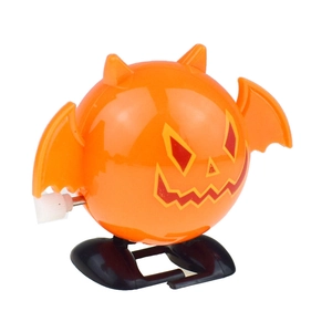Side view of wind-up Halloween pumpkin toy with orange wings and black mechanical feet