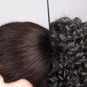Detail of curly black synthetic ponytail extension attachment on model's hair