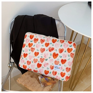 Close-up of quilted white laptop sleeve with red hearts on a stylish folding chair