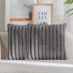 Detail of grey faux fur pillow with plush vertical stripes on a beige fabric sofa