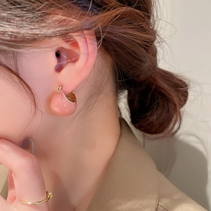 Detail shot of a model wearing pink enamel ball earrings with gold-plated geometric charms