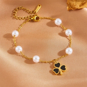 Gold stainless steel bracelet with white pearls and a black clover charm on satin