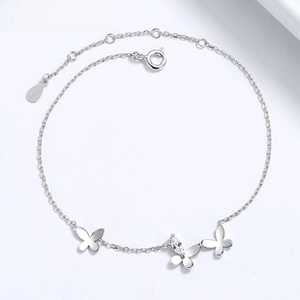Detail of 925 sterling silver bow bracelet featuring triple charms and teardrop zircon