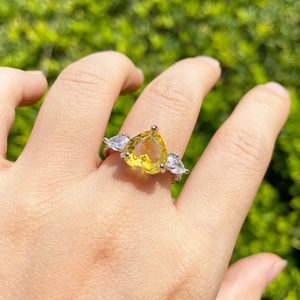 Close-up of yellow heart-shaped cubic zirconia ring with pear side stones on hand