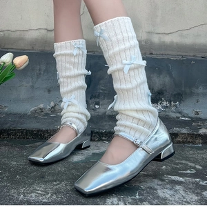 Détail de jambières en tricot avec nœuds bleu clair et chaussures Mary Jane argentées