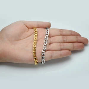 Detailaufnahme von goldenen und silbernen Figaro-Halsketten aus Edelstahl in der Hand