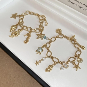 Detail of gold ocean-themed bracelets with starfish, seahorse and turtle charms