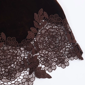 Gros plan sur du velours marron foncé avec broderie en dentelle complexe sur le bord