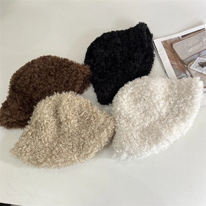 Flat lay of curly faux fur bucket hats in four colors with a fashion magazine