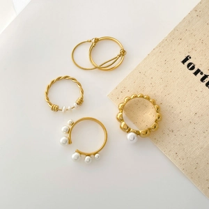 Set of four gold-plated pearl rings featuring twisted bands and minimalist open designs