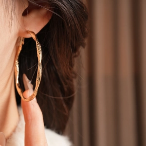 Close-up of vintage golden hoop earrings with irregular hammered texture on model