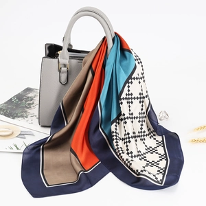 Dettaglio di sciarpa in raso a righe geometriche drappeggiata su borsa in pelle grigia