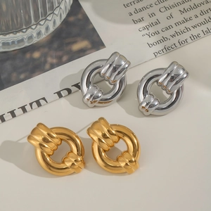 Elegant gold and silver titanium steel hoop earrings displayed on vintage newspaper background