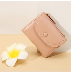 Detalle de cartera rosa corta con cierre de presión y textura de cuero sintético fino